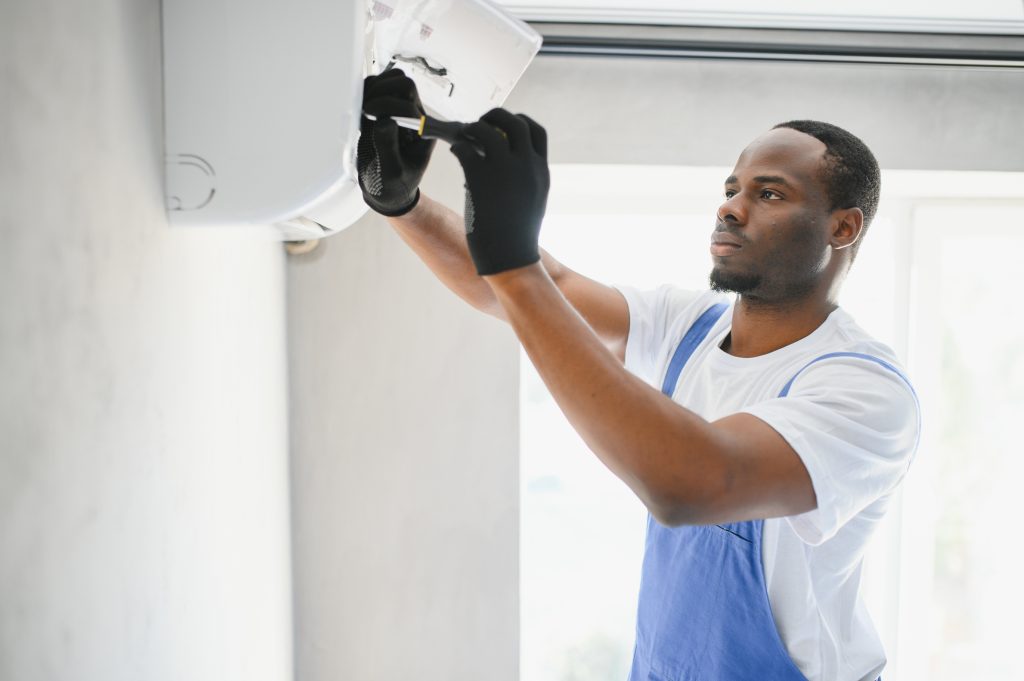 african american electrician repairing air conditioner indoors photo african american electrician repairing air conditioner indoors photo