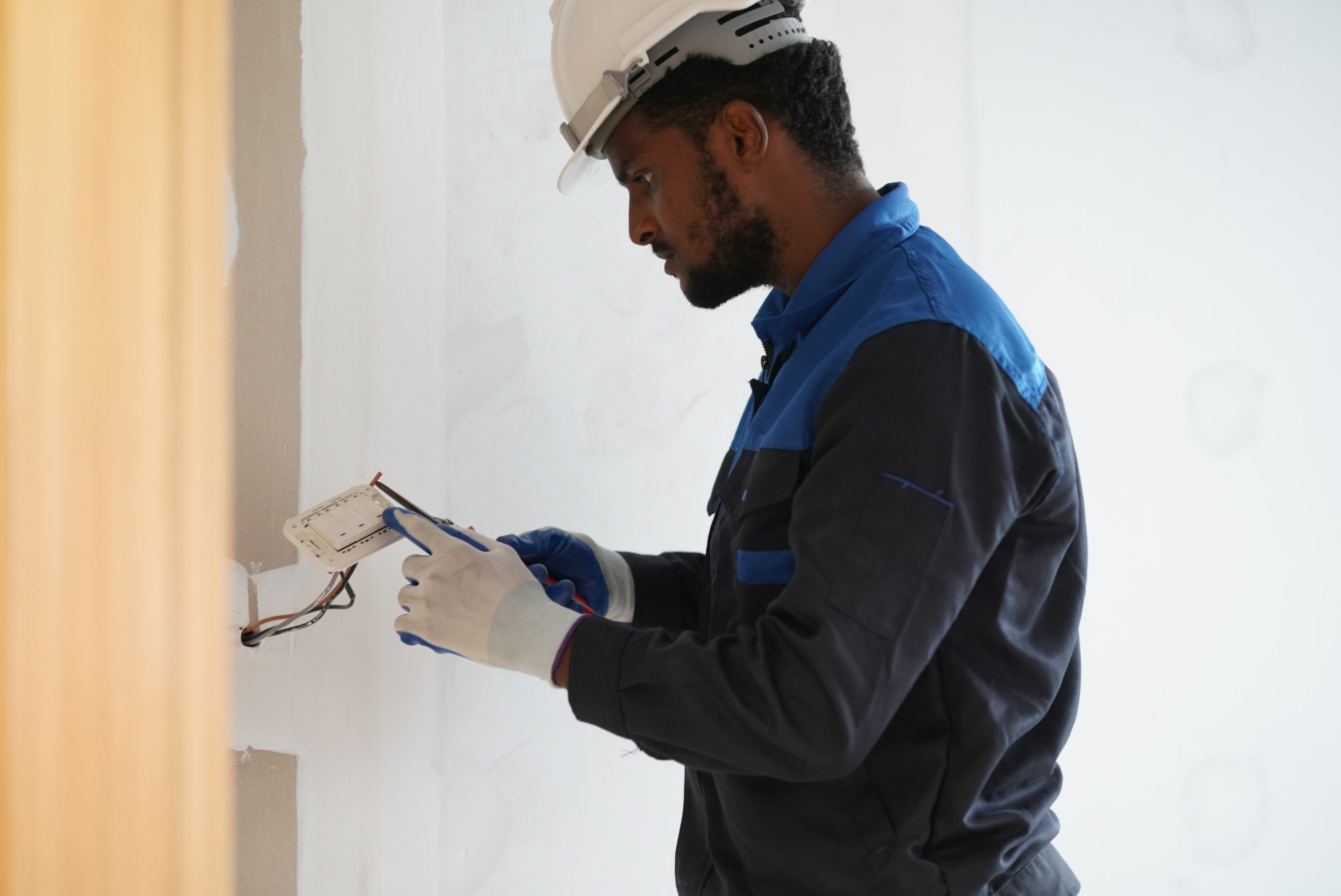 a man in a hard hat and blue gloves is working on a wall photo