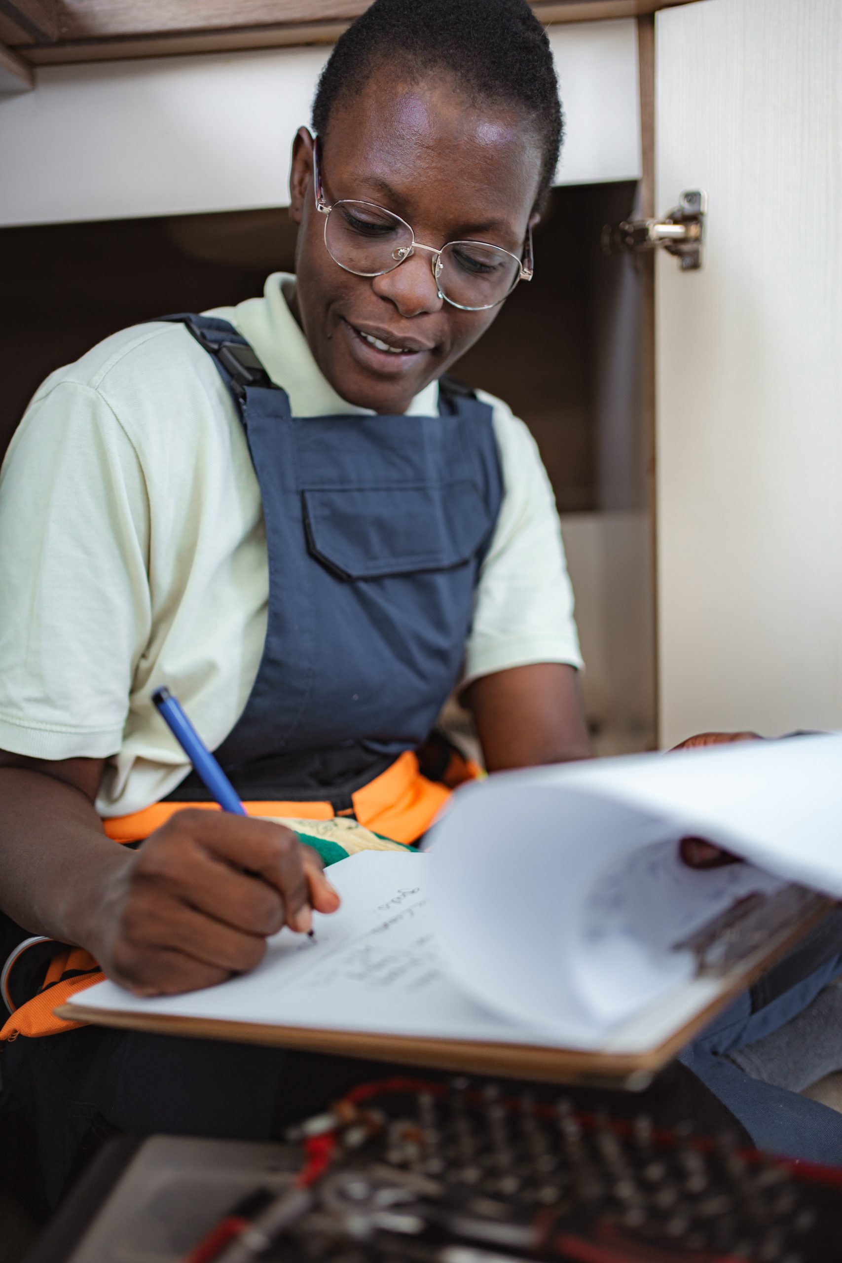 female electrician taking notes and planning her work under the sink photo (1)